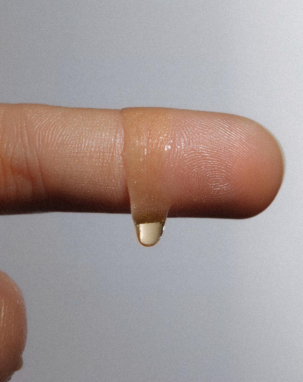 Close-up of a finger with a drop of liquid on a plain background