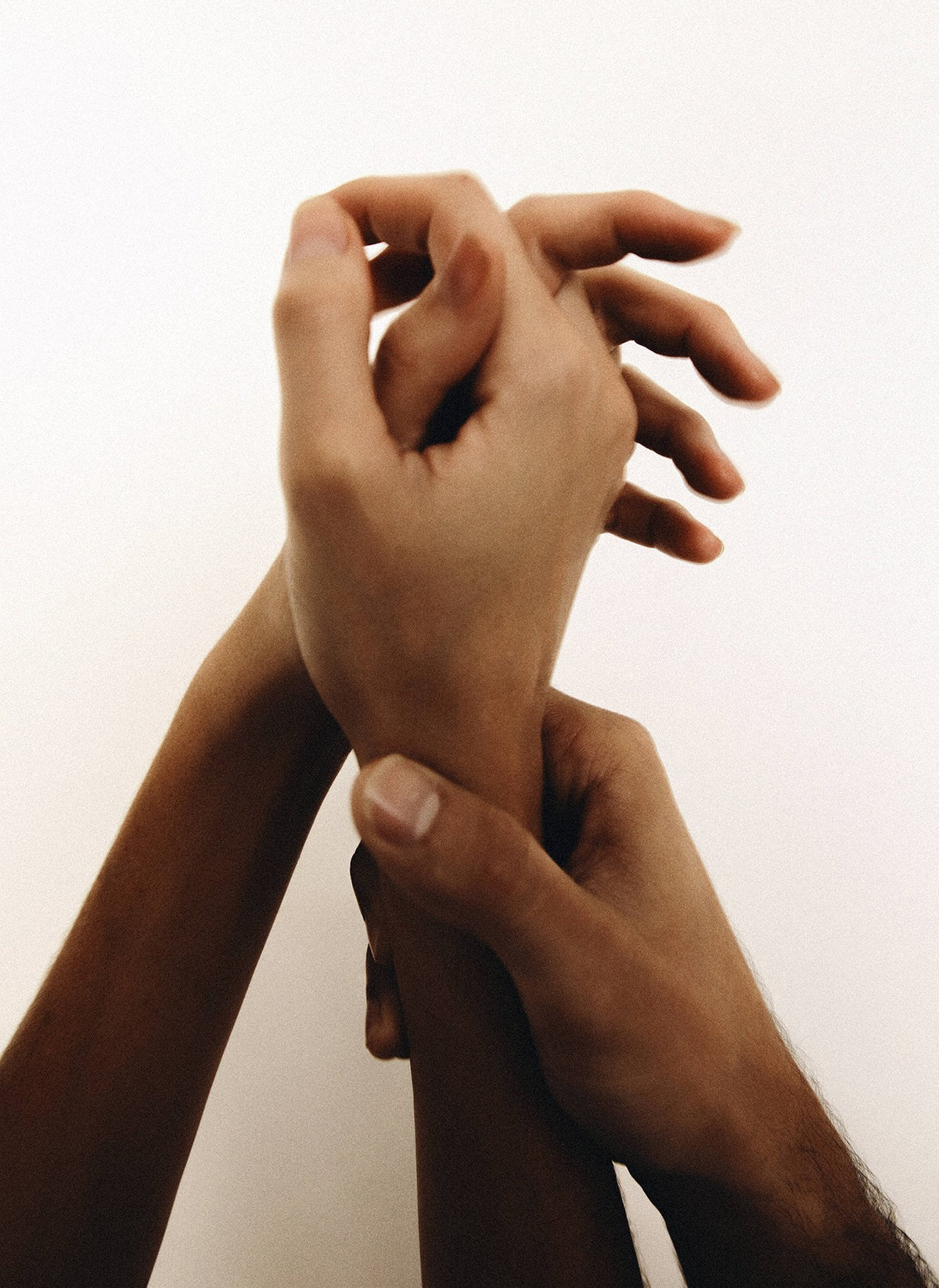 Two hands holding a wrist against a pale wall